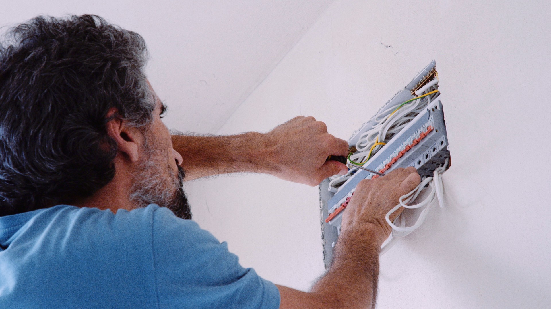 Man works on mains fuse box in a new home. DIY.